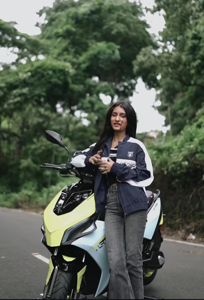 Creator posing with a TVS NTORQ scooter on a forest road