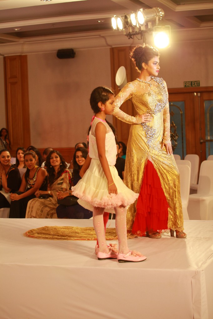 Designer in a gold gown with a child model on the Pranaah Yaama runway