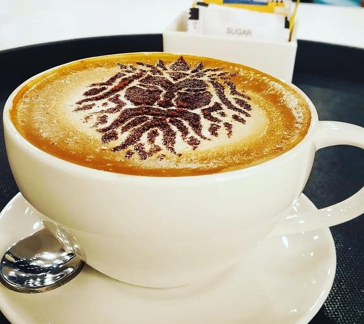 Coffee cup with The Brewing Company logo rendered as latte art